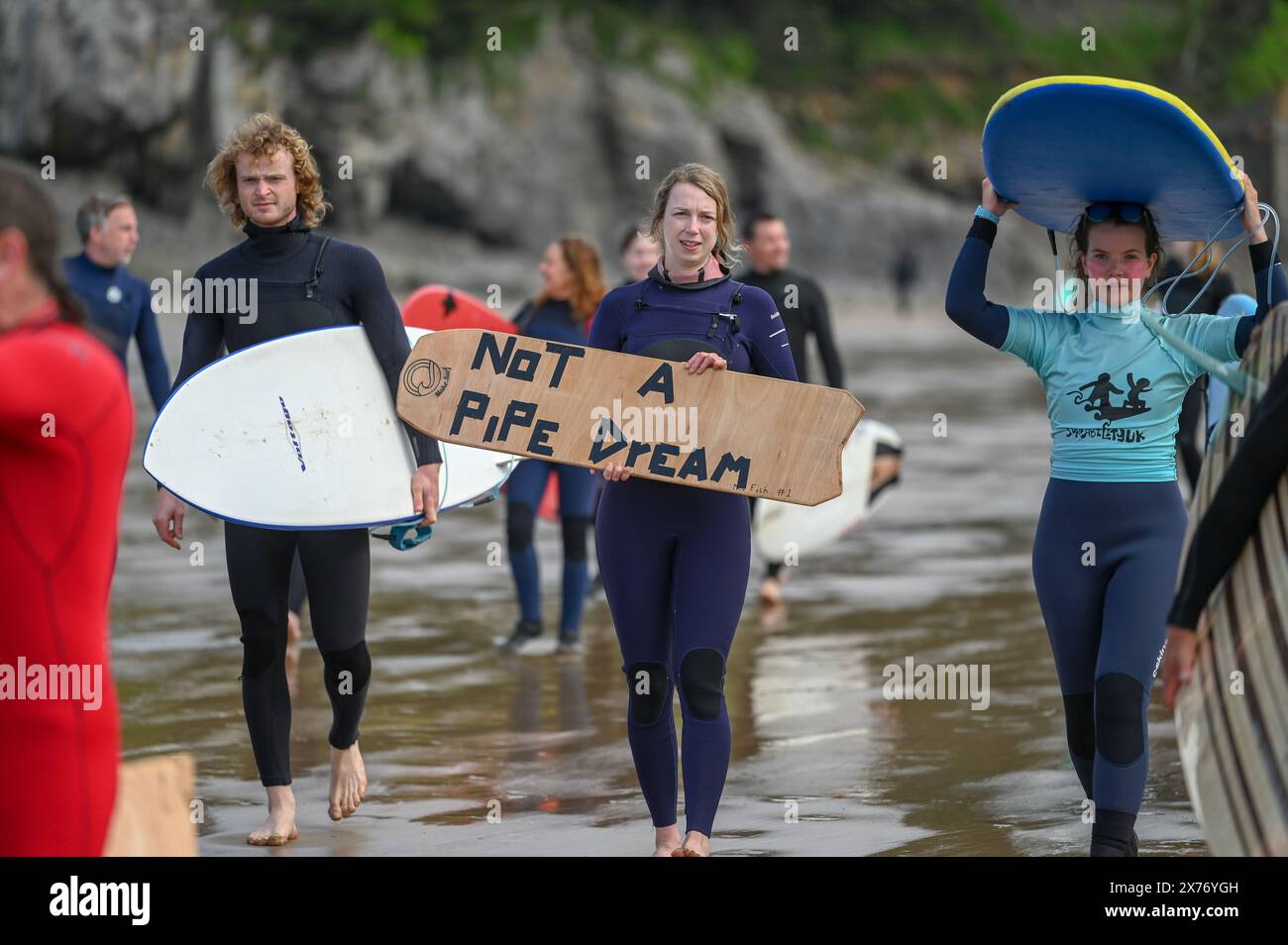 Le persone prendono parte a una pagaia a Caswell Bay a Swansea, parte di un evento nazionale organizzato dai surfisti contro le acque reflue, per chiedere la fine dell'inquinamento delle acque reflue e protestare contro le pratiche attuali di fognatura che entrano in mare. Foto Stock