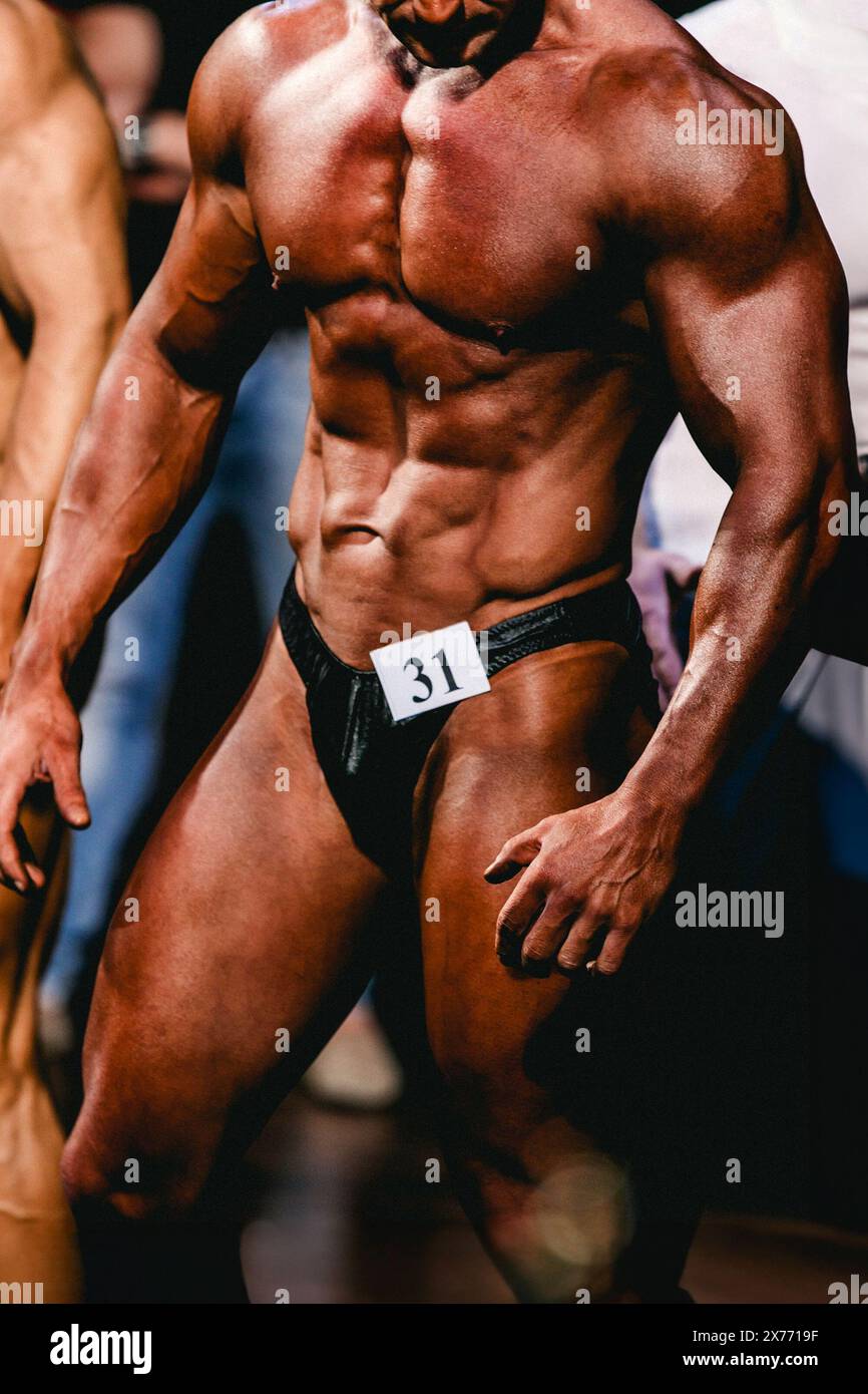 uomo bodybuilder atleta mostra una posa frontale nella competizione di bodybuilding Foto Stock