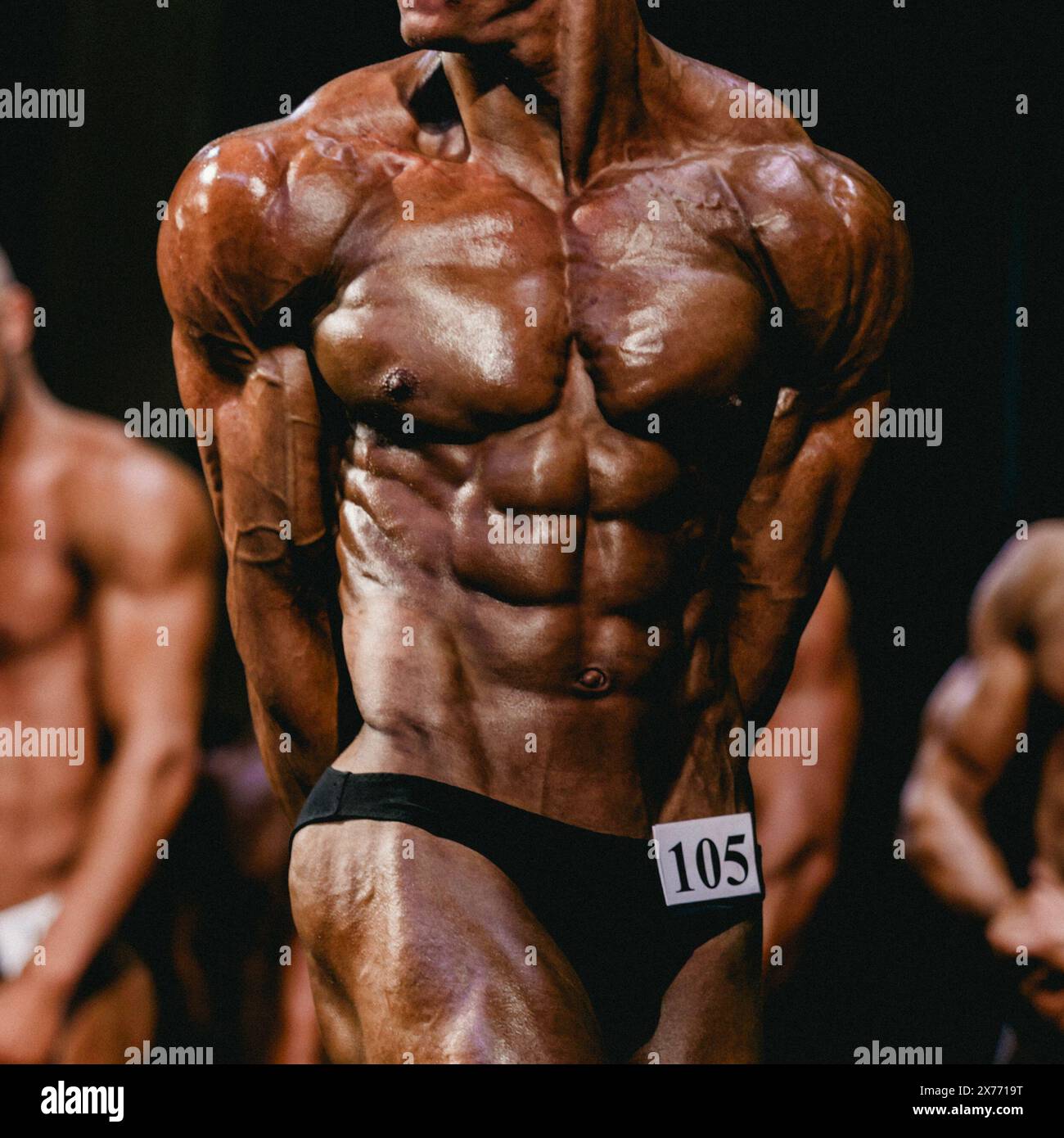 l'atleta bodybuilder mostra tricipiti laterali in posa per le competizioni di bodybuilding Foto Stock