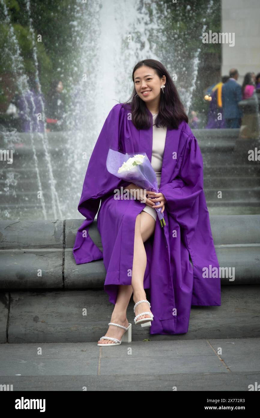 Dopo la cerimonia di laurea della NYU 2024, una bella donna asiatica americana posa per delle foto tenendo in mano dei fiori. Al Washington Square Park di Manhattan. Foto Stock