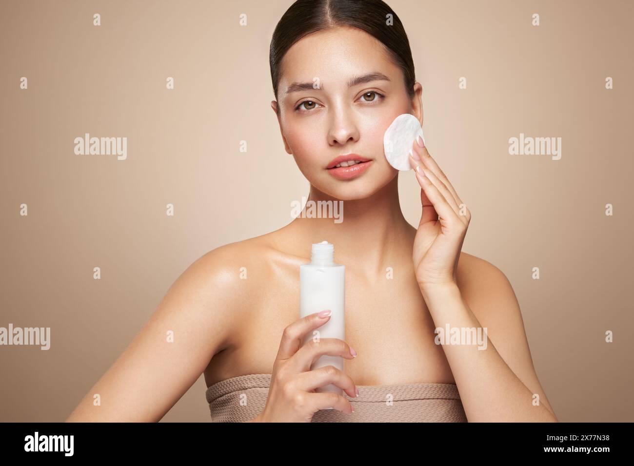 La ragazza tiene in mano il tampone di cotone mentre pulisce il viso con latte cosmetico. Rimozione della pulizia del trucco per la cura della pelle. Cura di base della pelle del viso Foto Stock