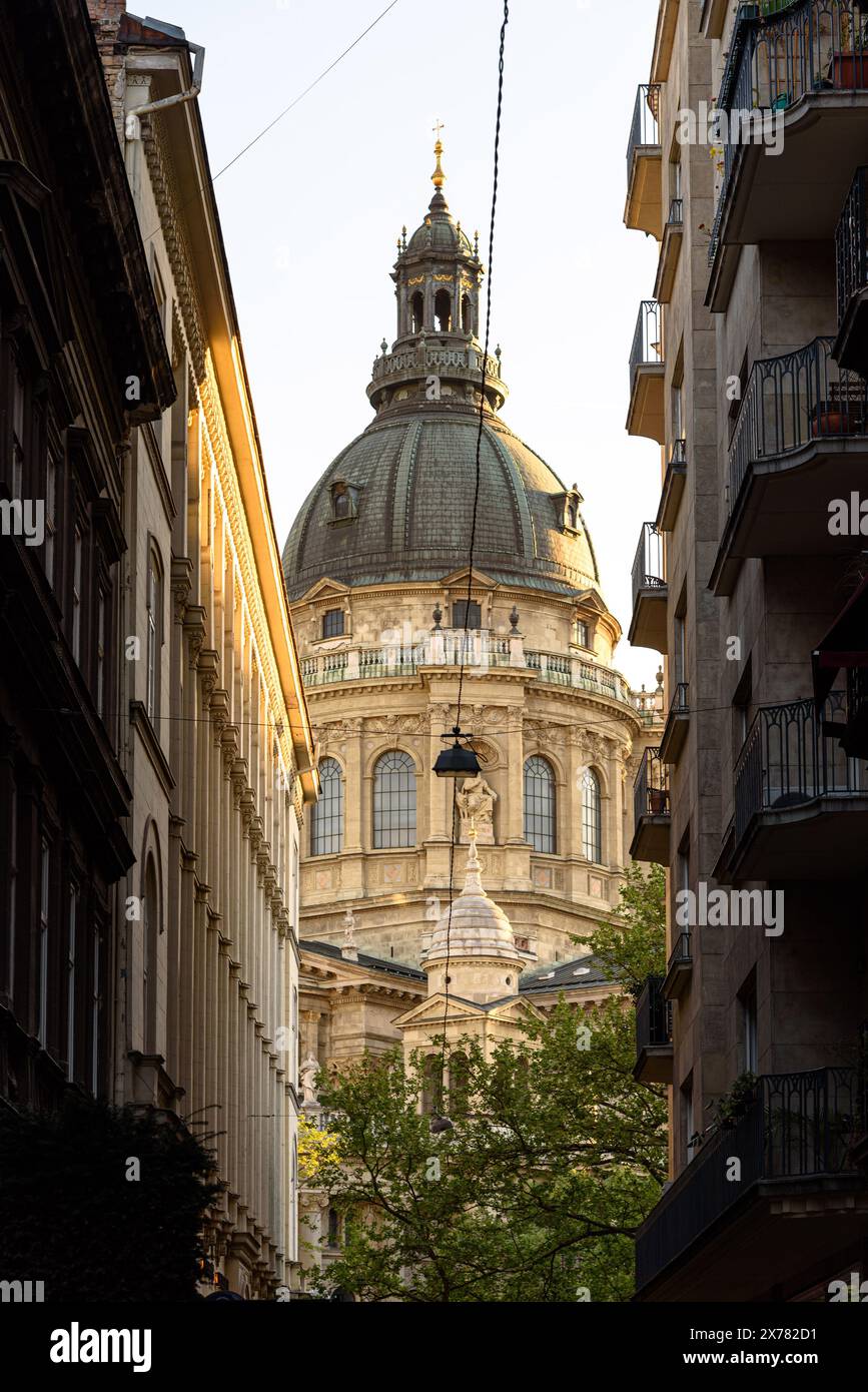 La cupola della basilica di Santo Stefano, vista tra due edifici durante l'ora d'oro di Budapest Foto Stock