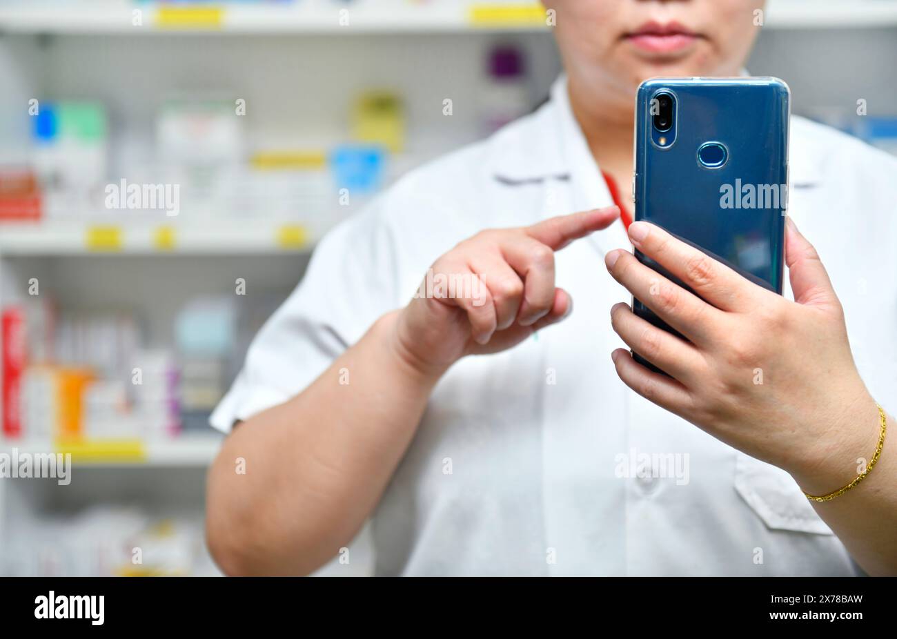 Un farmacista possiede un telefono cellulare per ricevere la prescrizione di un medico, preparare la medicina e controllare la medicina in una farmacia. Foto Stock