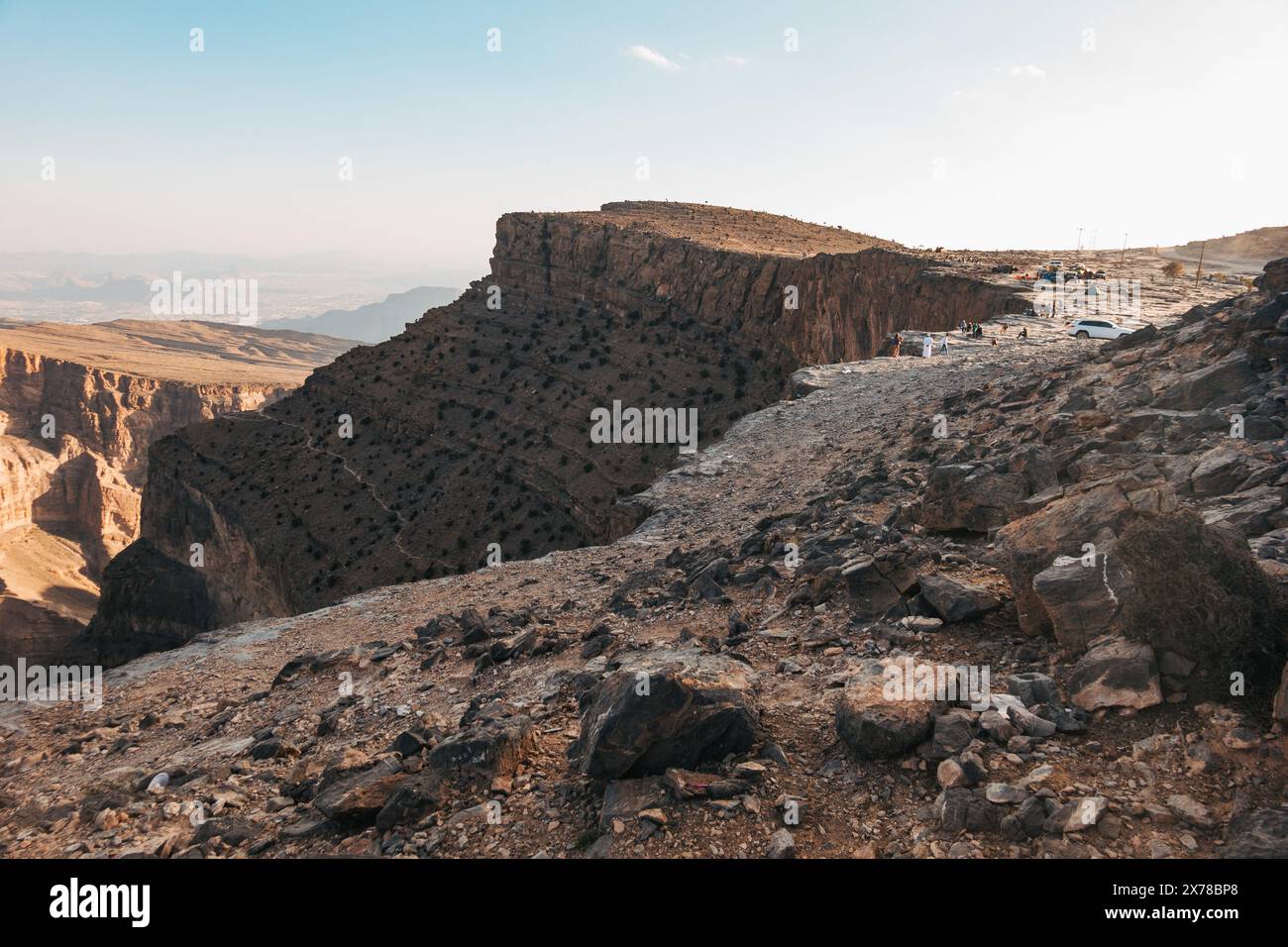 Le persone si radunano e si accamparono ai margini del canyon Jebel Shams in Oman, godendo di viste panoramiche e attività all'aperto. Foto Stock