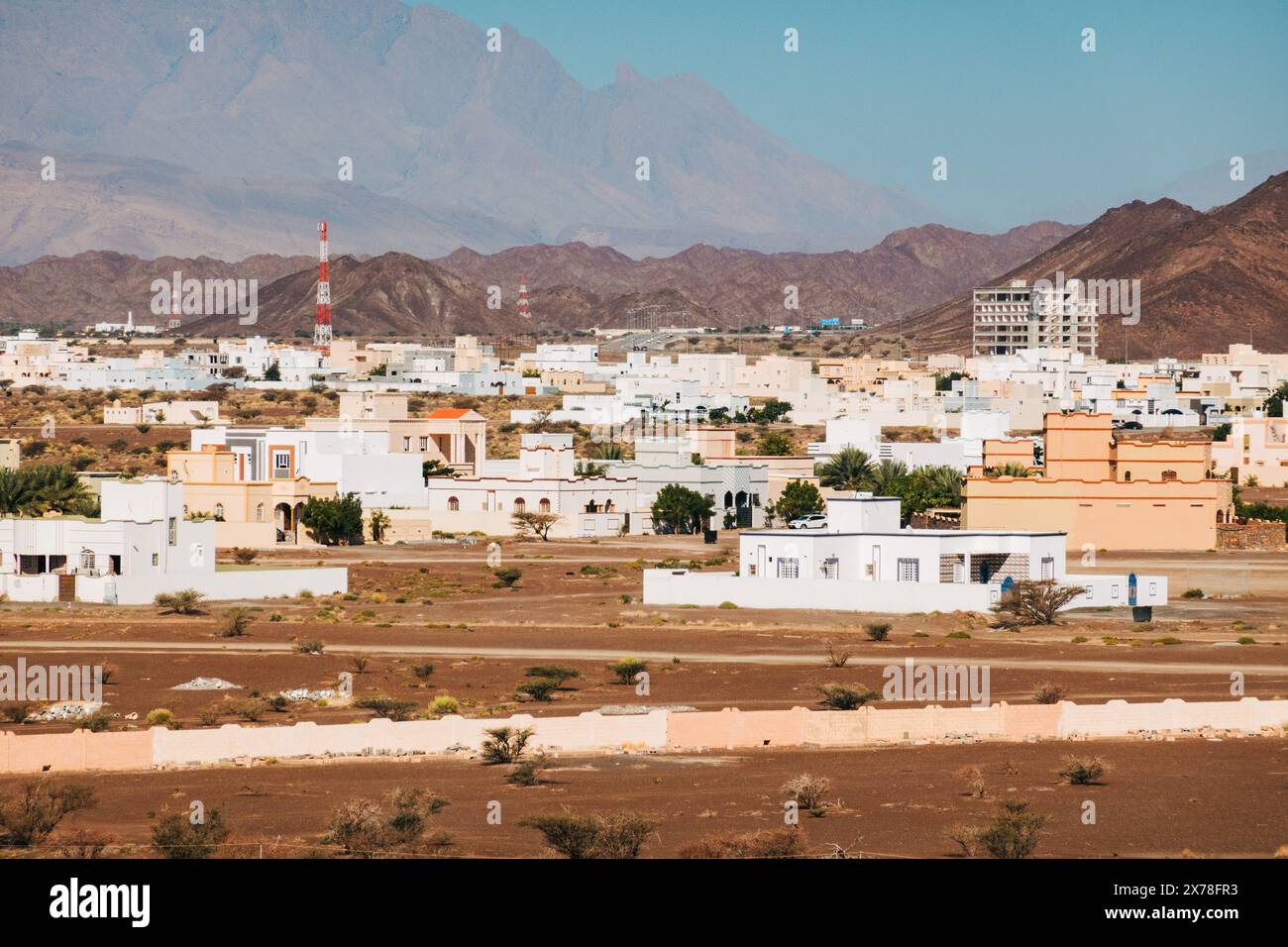 Case bianche in stile modernista regionale araba costruite nella città di Bahla, Oman. Contro i monti Hajar Foto Stock
