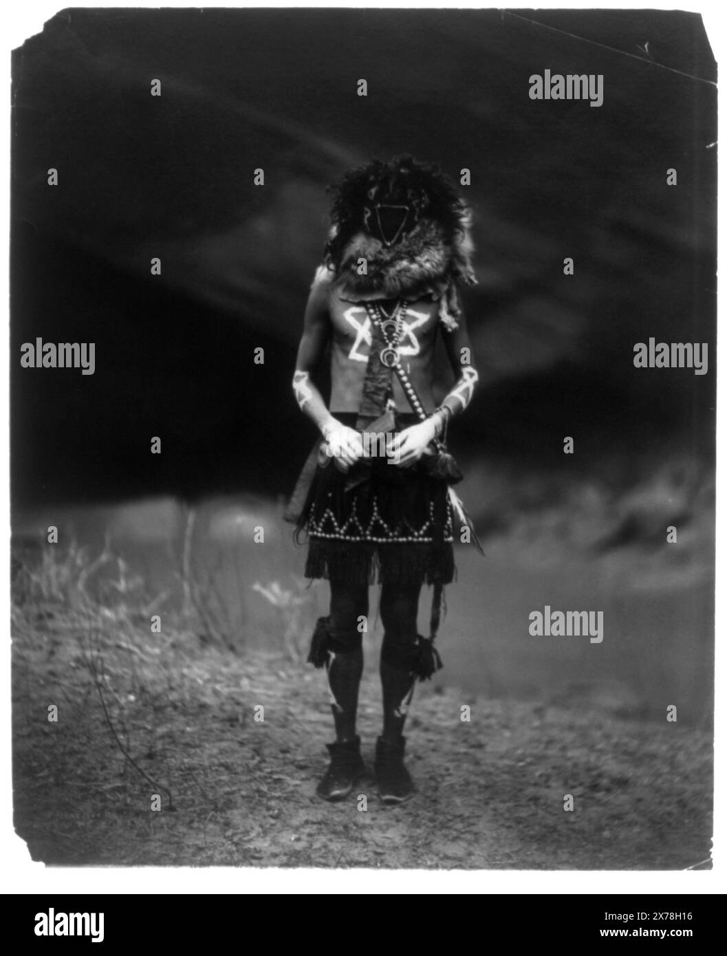 Tobadzischini Navaho, didascalia dalla mostra "American Treasures Memory": Portfolio of the North American Indian. Dagli anni '1890 agli anni '1930, Edward S. Curtis fotografò circa ottanta diversi gruppi di nativi americani, tra cui i loro abiti tradizionali, i loro mestieri e le loro case. Pubblicò un'opera di ventotto volumi, The North American Indian, che abbracciava la nozione romantica che lui e altri bianchi americani avevano riguardo agli indiani sconfitti. Questa immagine di Tobadzischini, (dio della guerra), partecipante alla danza Yebechai, un rituale di nove giorni che combina rituale e medicina ancora oggi praticato Foto Stock