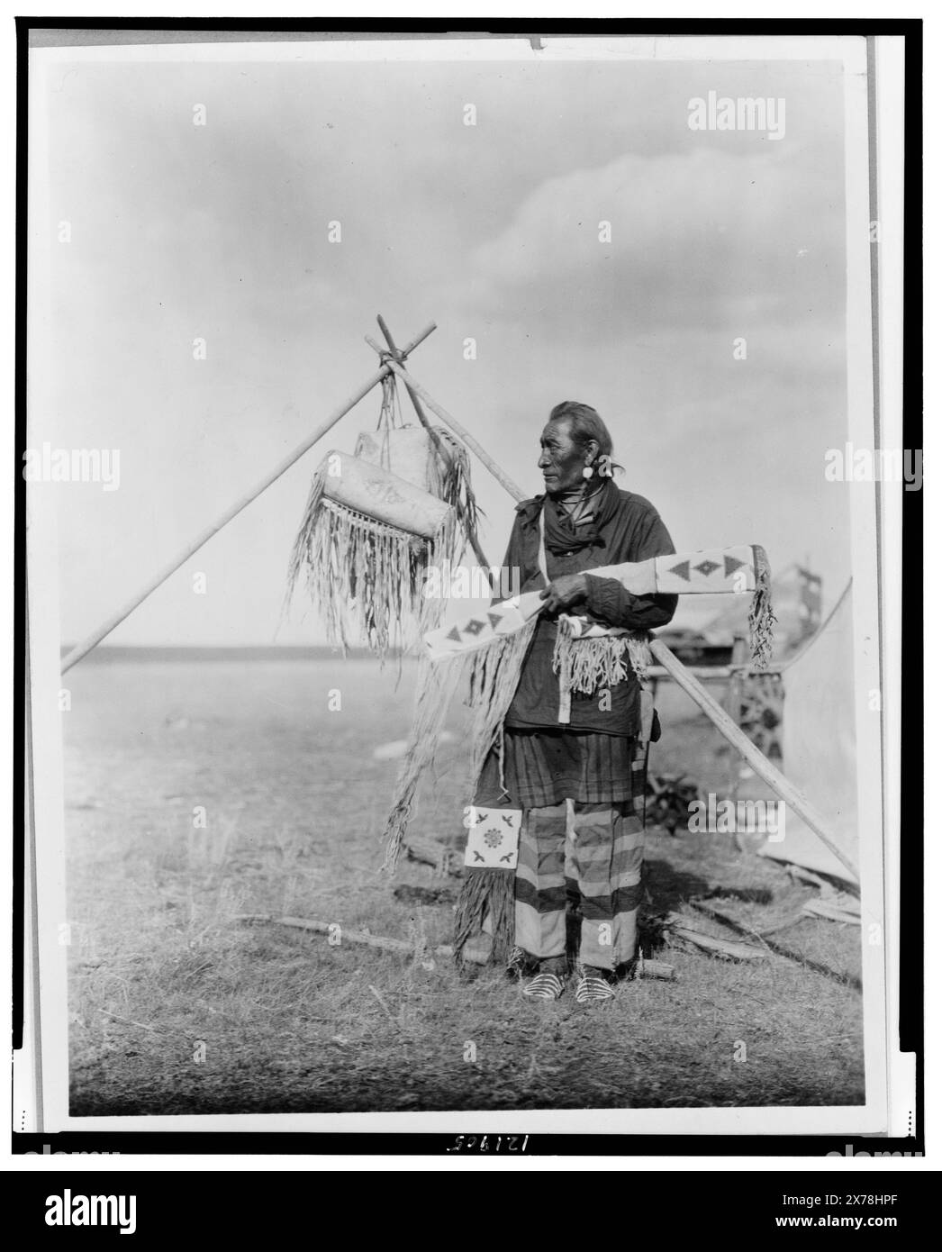 In a Blackfoot Camp, Edward S. Curtis Collection ., pubblicato in: The North American Indian / Edward S. Curtis. [Seattle, Washington.] : Edward S. Curtis, 1907-30, v. 18, p. 114.. Indians of North America, abbigliamento e abbigliamento, 1920-1930. , Siksika Indians, Clothing & dress, 1920-1930. , Oggetti cerimoniali, 1920-1930. Foto Stock