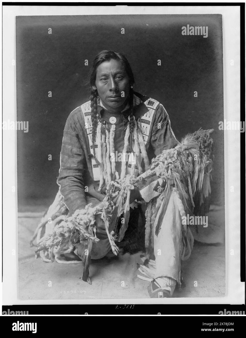 A medicine pipe Piegan, nome su verso: Broad Tail., Edward S. Curtis Collection ., Curtis no. 3096-09., pubblicato in: The North American Indian / Edward S. Curtis. [Seattle, Washington.] : Edward S. Curtis, 1907-30, v. 6, PL. 199.. Coda larga. , Indians of North America, Clothing & Dress, 1910. , Indiani del Piegan, abbigliamento e abbigliamento, 1910. , Calumets, 1910. Foto Stock