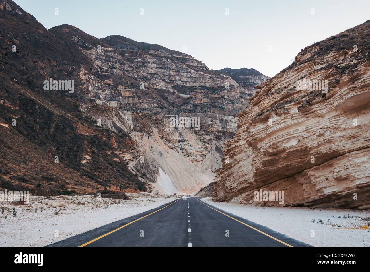 Empty Mountain Road che si snoda attraverso un canyon al tramonto nella campagna di Salalah, nel sud dell'Oman Foto Stock