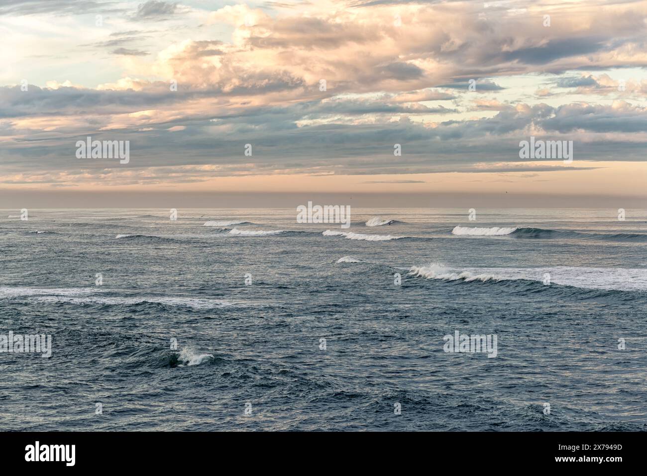 Onde infranti che si infrangono contro un cielo nuvoloso all'alba. Foto Stock