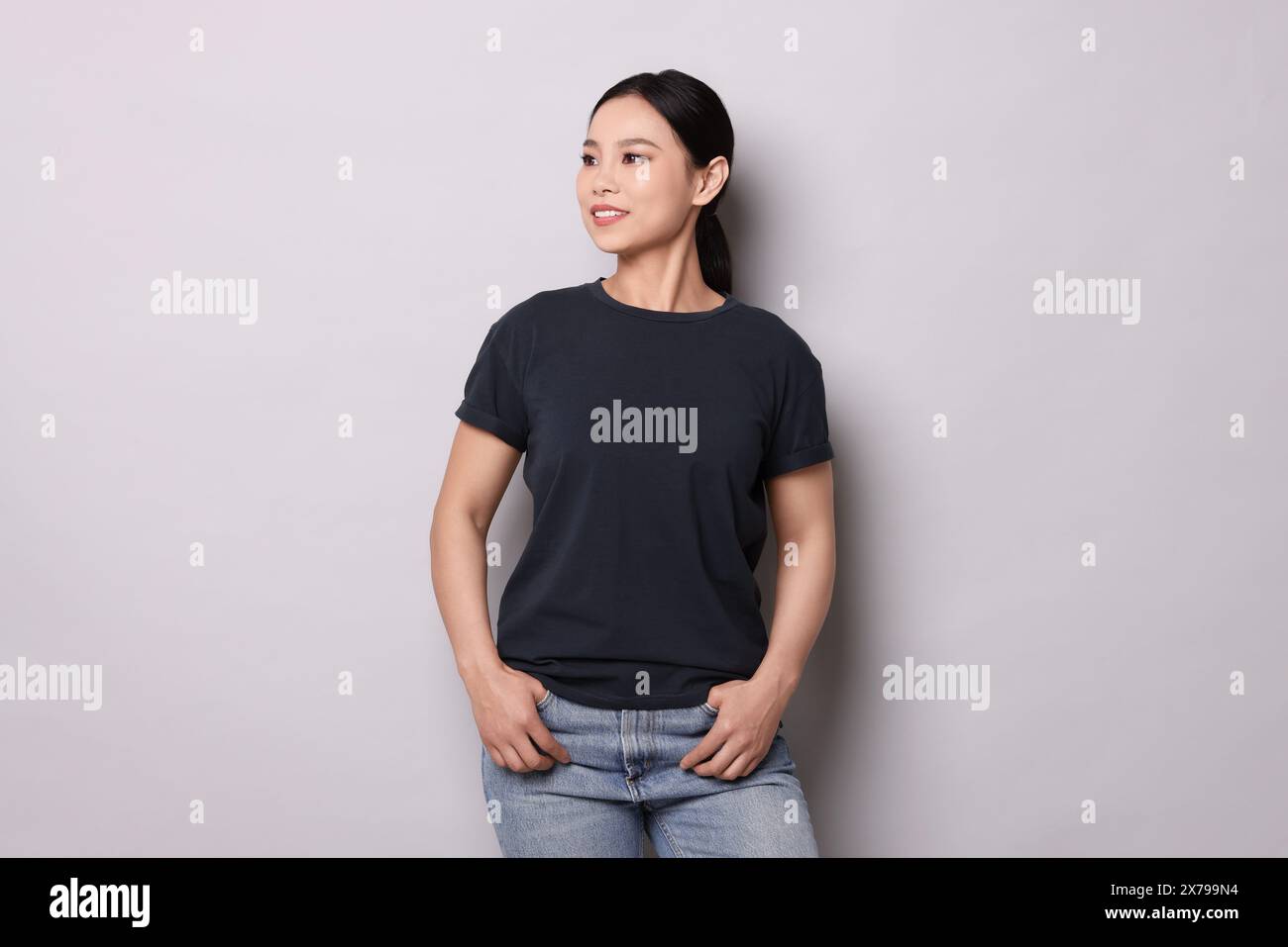 Donna che indossa una t-shirt nera su sfondo grigio chiaro Foto Stock