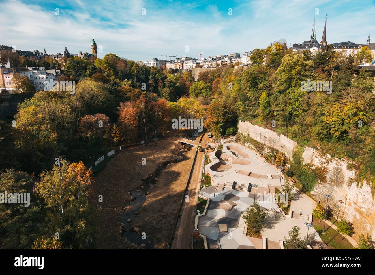 Vista aerea della valle Petrusse a Lussemburgo, con alberi lussureggianti, un letto di fiume asciutto e un moderno skatepark. Foto Stock