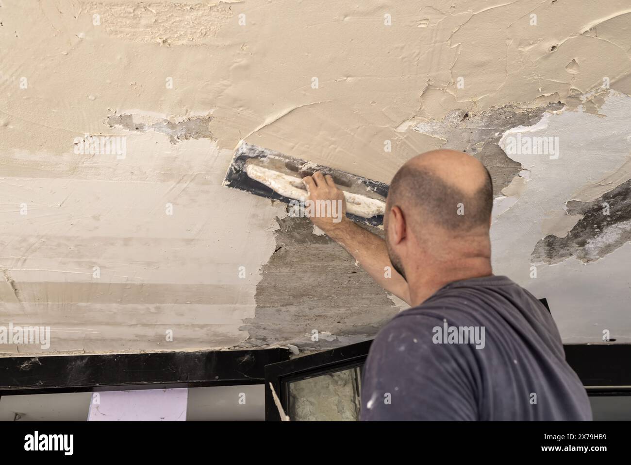 Il costruttore applica intonaco o cemento al soffitto. Adatto per progetti di ristrutturazione e costruzione Foto Stock