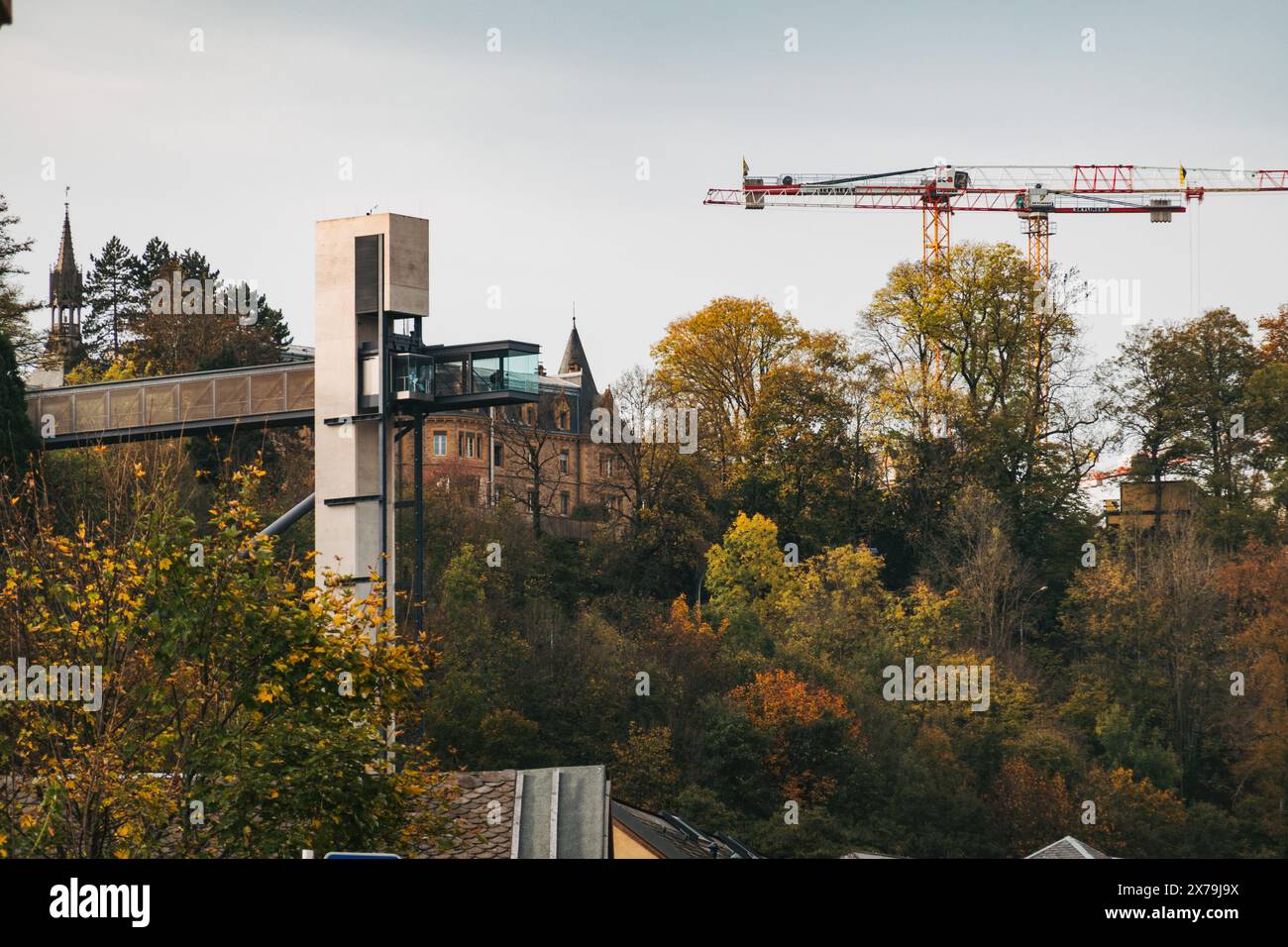 Vista dell'ascensore panoramico di Pfaffenthal nella città di Lussemburgo con alberi autunnali e gru da costruzione sullo sfondo. Foto Stock