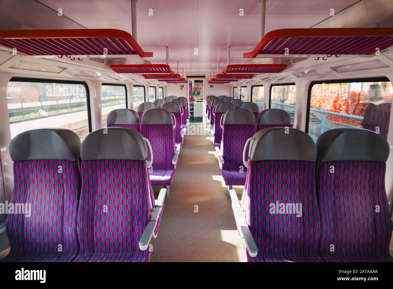 Sedili viola in configurazione 2-2 e grandi finestre all'interno di un vagone ferroviario vuoto LTG Link tra Vilnius e la Lituania Foto Stock