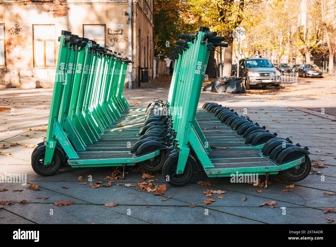 File di scooter elettrici Bolt parcheggiati e pronti per il noleggio a Kaunas, Lituania. Gli utenti aprono un'app sul loro telefono per sbloccarla e giocarci Foto Stock