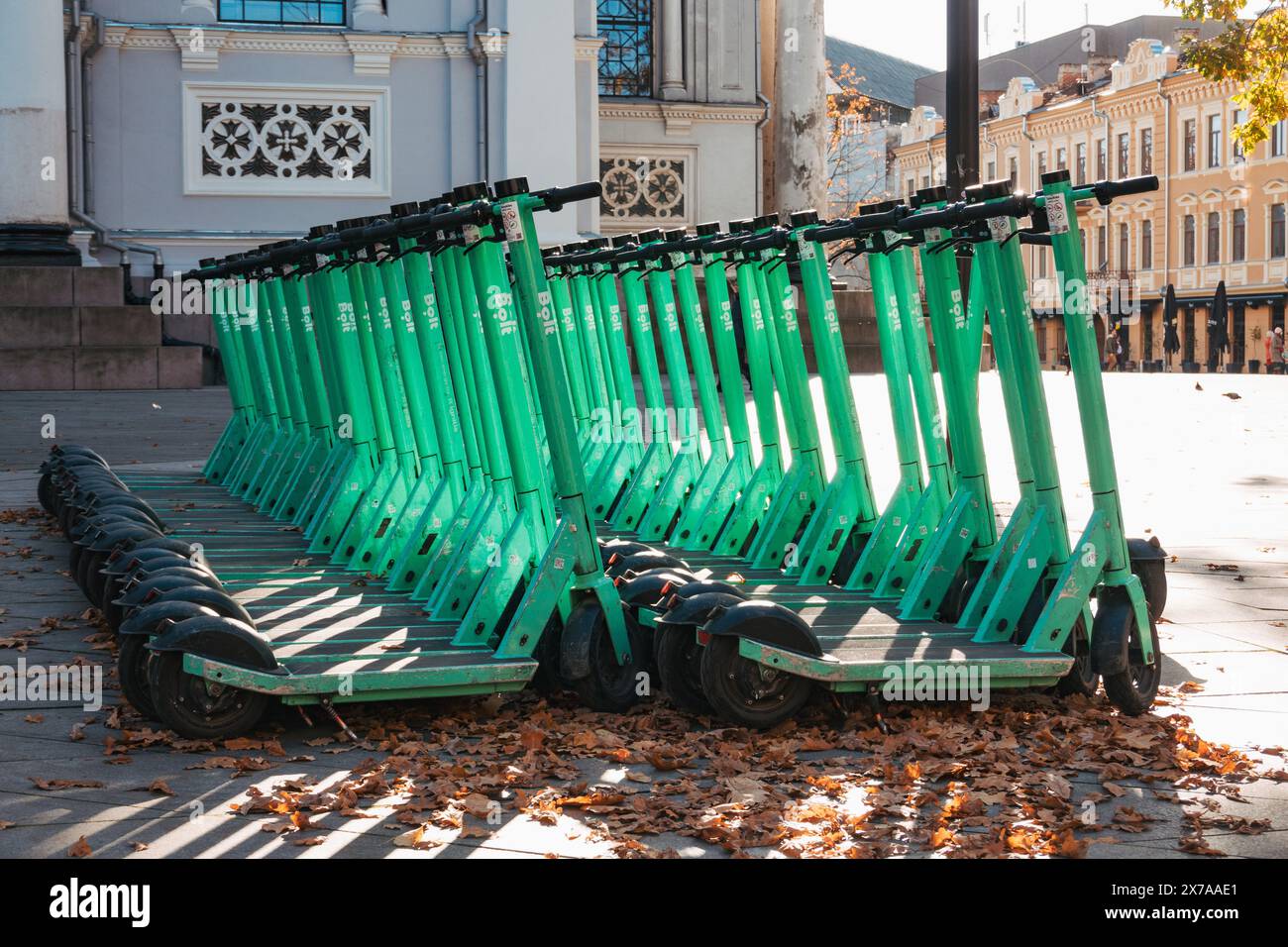 File di scooter elettrici Bolt parcheggiati e pronti per il noleggio a Kaunas, Lituania. Gli utenti aprono un'app sul loro telefono per sbloccarla e giocarci Foto Stock