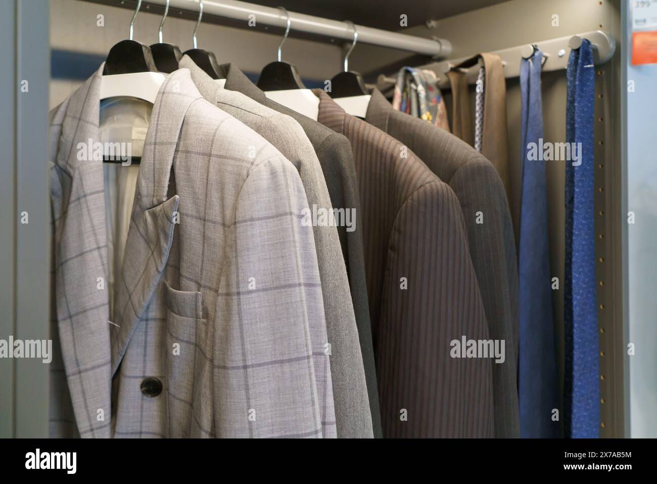Armadio elegante e organizzato con una collezione di abiti da uomo Foto Stock