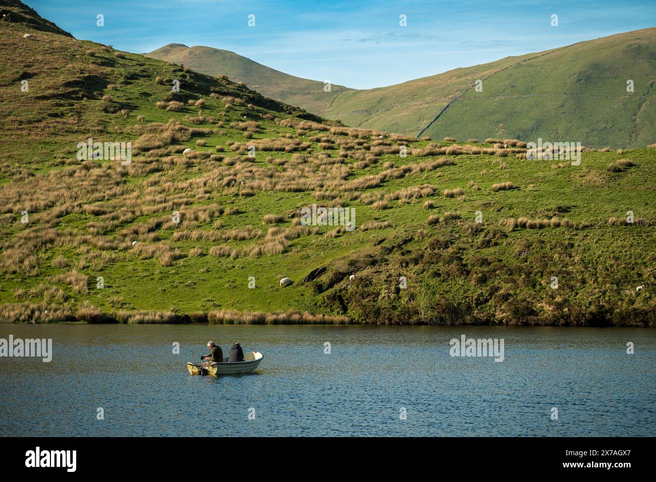 Pescatori che pescano da una barca a Llyn Dywarchen nel Parco Nazionale di Eryri, Galles, con Yr Wyddfa in lontananza. Foto Stock