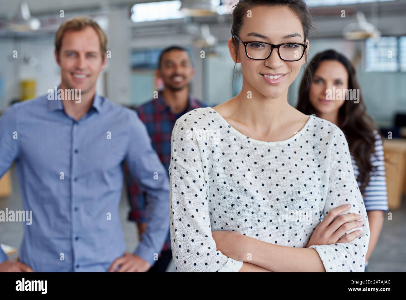 Donna, ritratto e braccia incrociate con i colleghi per leadership o azione affermativa, fiducia o designer. Colleghi, faccia e su di noi come Foto Stock