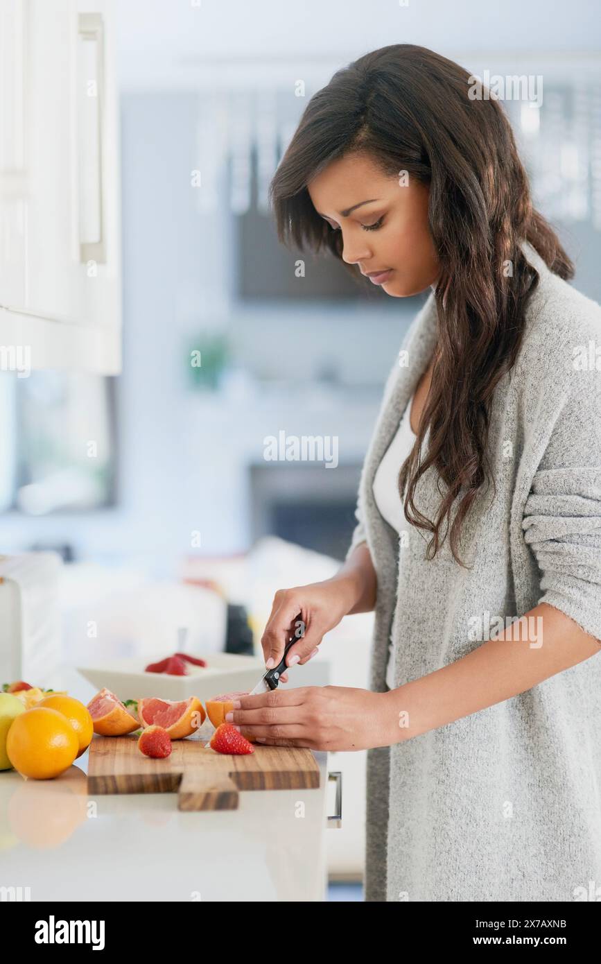 Frutta, insalata e donna in cucina per colazione con benefici di vitamina c, nutrizione e dieta. Sano, cibo e ragazza fetta di fragola organica e. Foto Stock