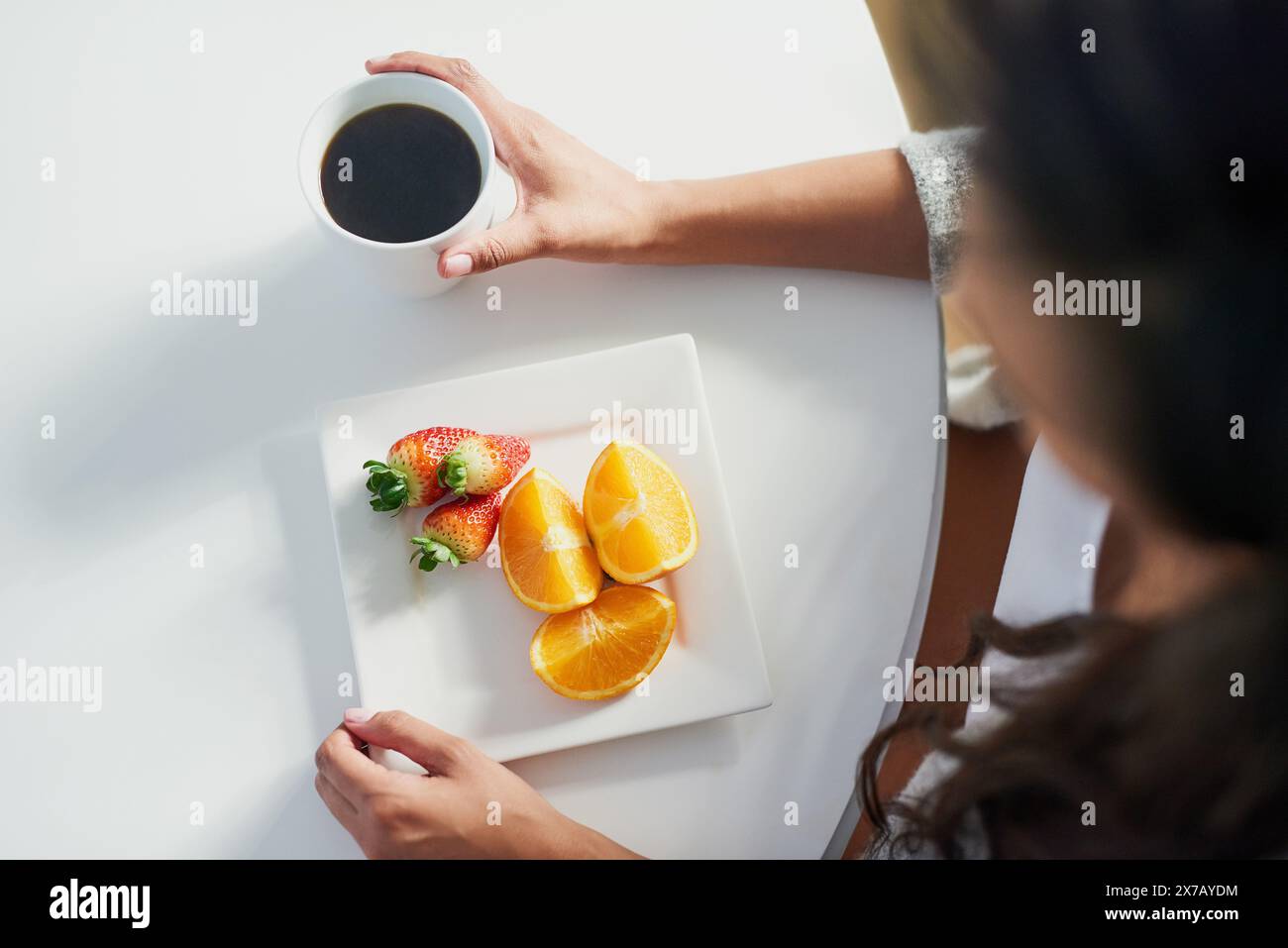 Frutta, caffè e sopra persona con colazione al mattino per i benefici della nutrizione nella dieta. Sano, cibo e donna bere espresso sul tavolo in casa Foto Stock