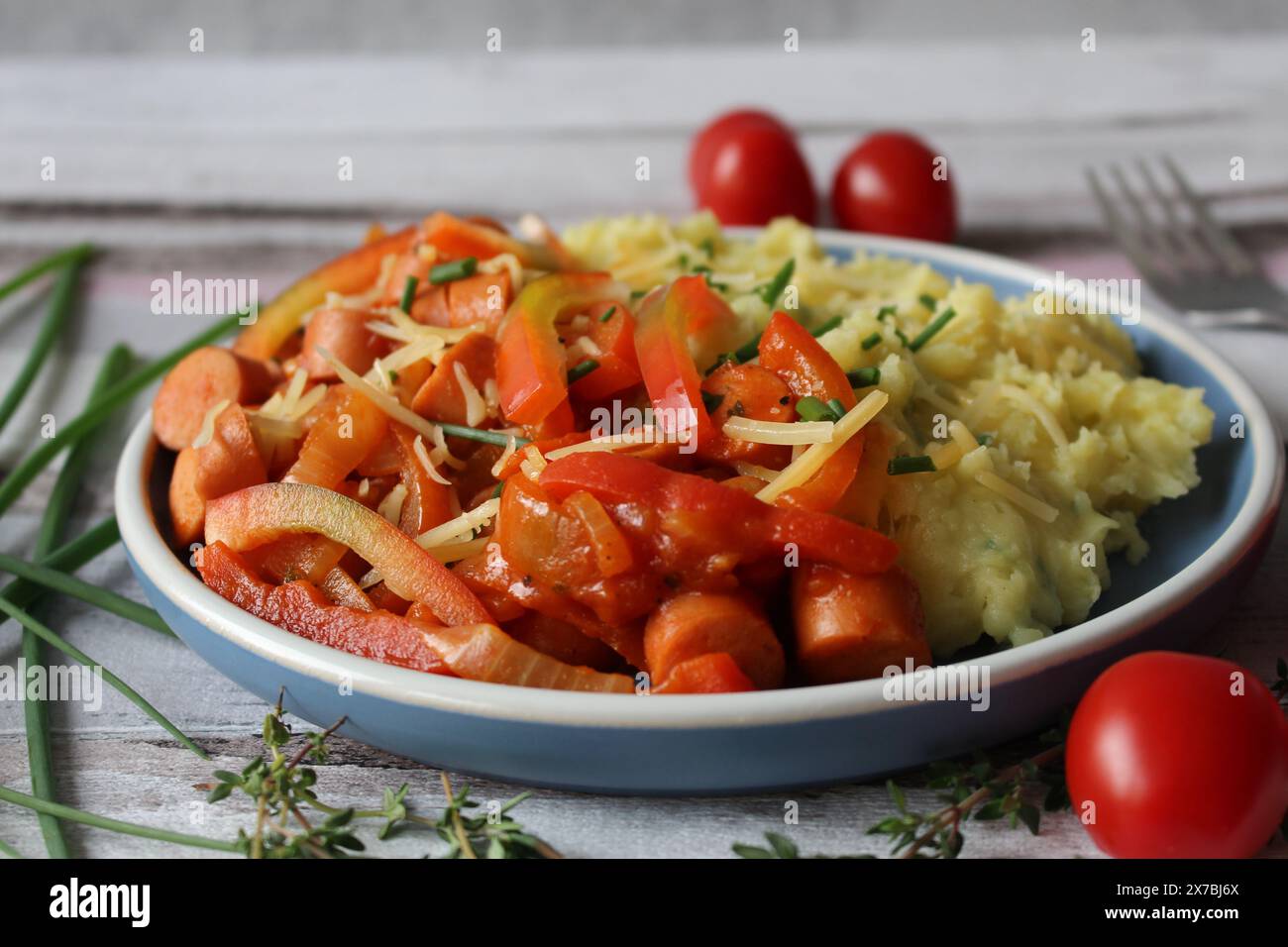 Stufato di salsiccia di patate con peperoni, pomodori e timo fresco Foto Stock