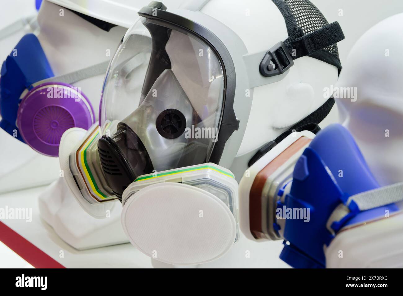 Gruppo di maschere di protezione respiratoria assortite su teste di manichino Foto Stock