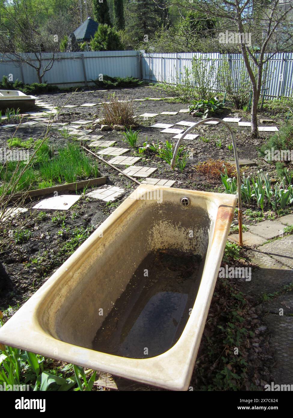 Cortile di cottage con vecchia vasca in ghisa per raccogliere acqua e innaffiare piante in siccità. Orto. Foto Stock