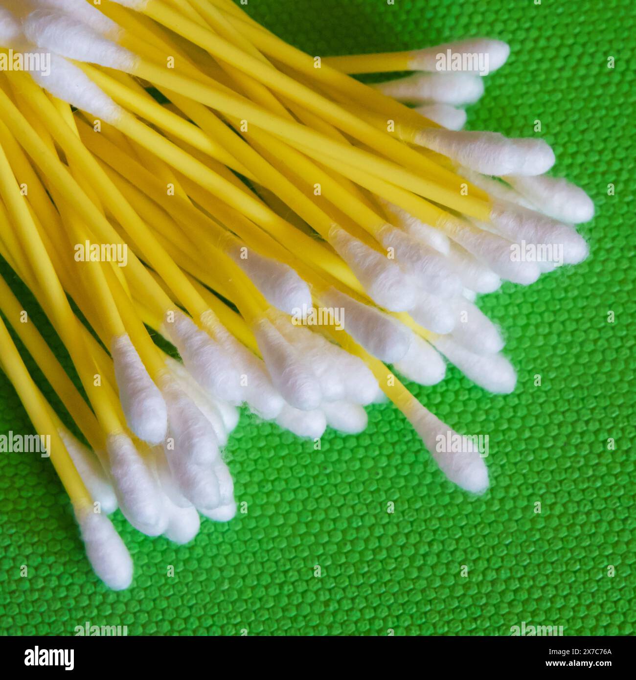 Materiali di consumo per la pulizia. Bastoncini di cotone con testa bianca, ambiente verde vivace. Foto Stock