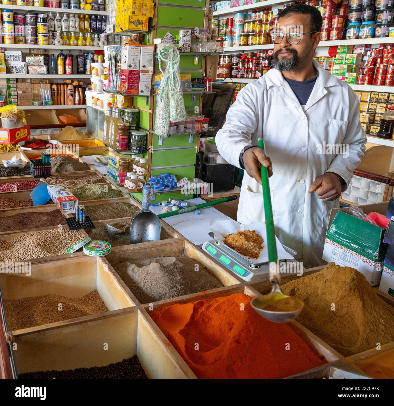 Er-Rich, Marocco - 7 marzo 2024: Negoziante marocchino che mescola spezie nel suo negozio nel mercato di er-Rich Foto Stock