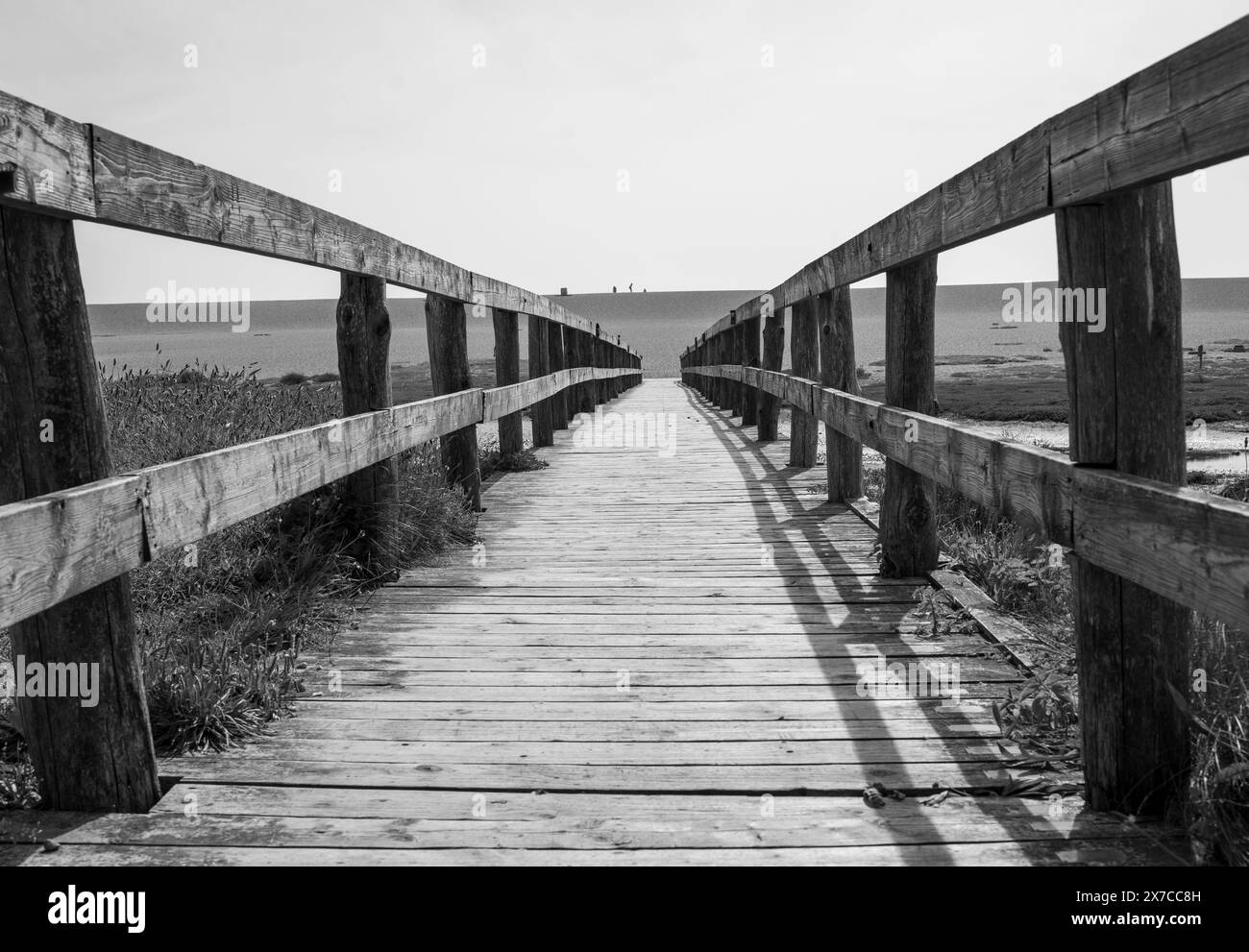 Scene di spiaggia da Chesil Beach nel Dorset che guardano verso la spiaggia, incluso un ponte su un'insenatura d'acqua. Foto Stock