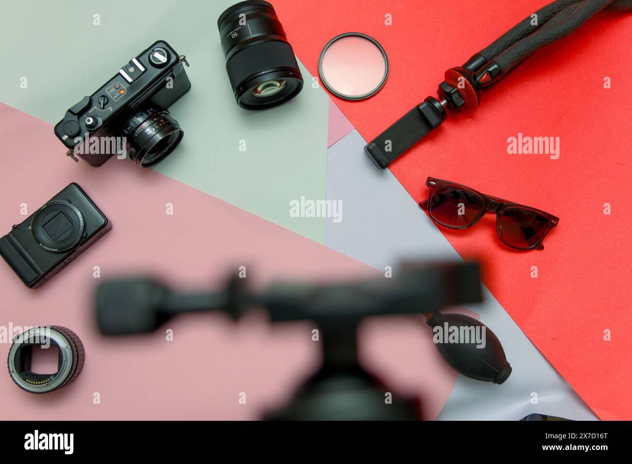 Una vivace struttura piatta che mostra le attrezzature essenziali di un fotografo professionista, tra cui una fotocamera, obiettivi, filtri, treppiede, e schede di memoria. Foto Stock