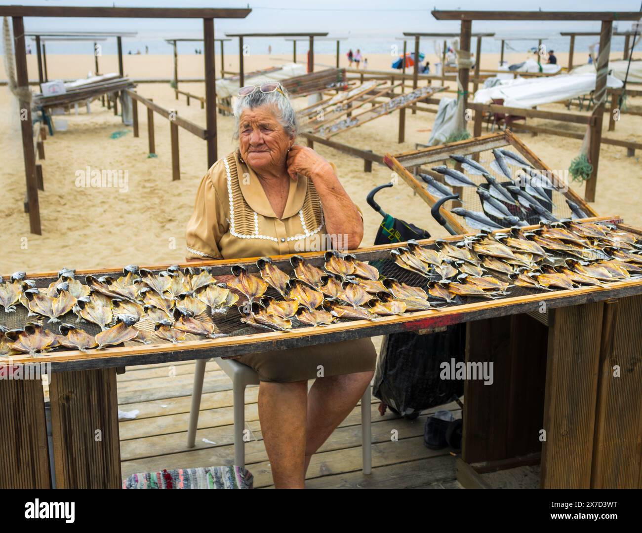 Donna che vende pesce essiccato al sole sulla spiaggia di Nazare, in Portogallo Foto Stock