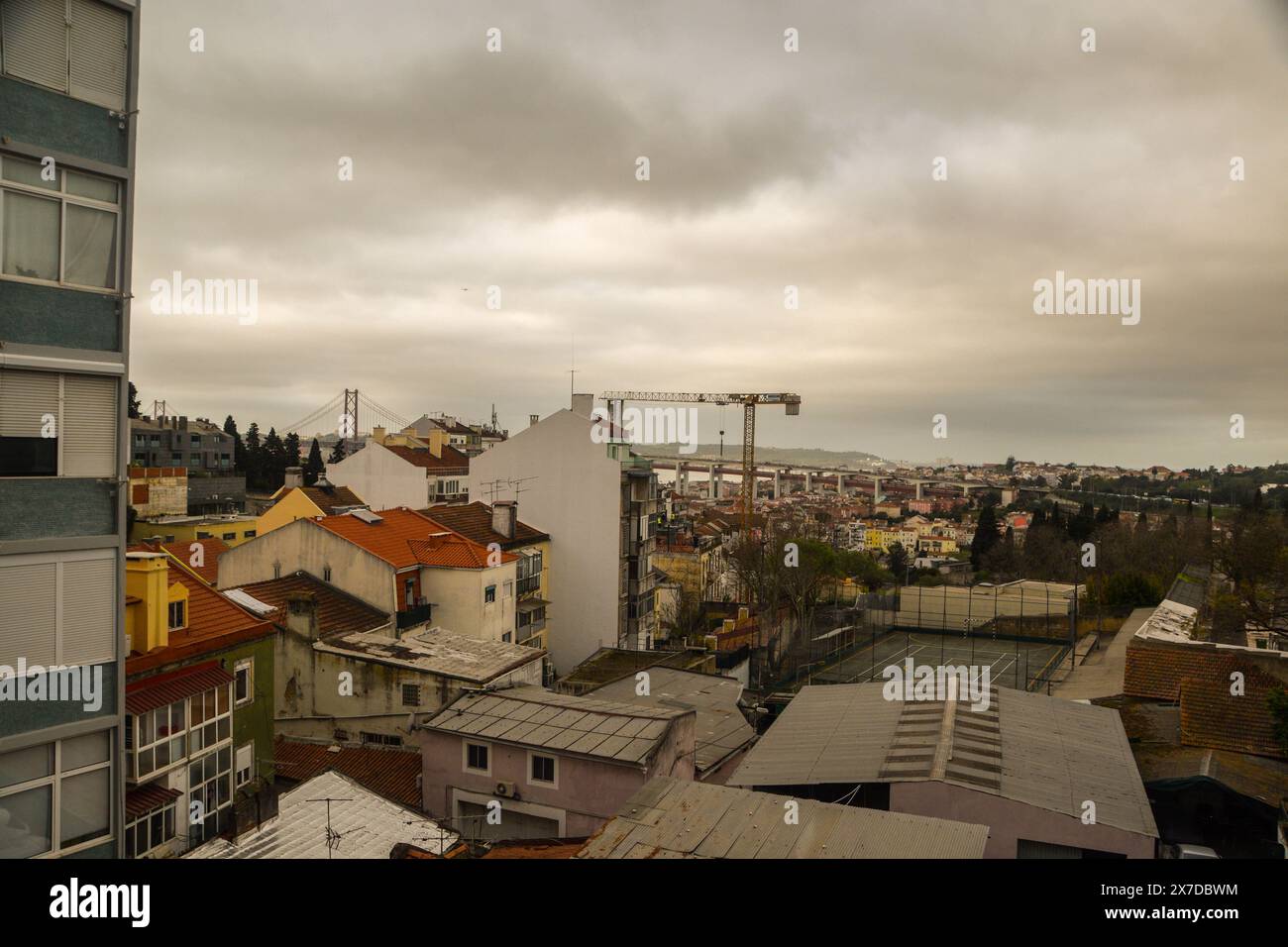 Vista generale di un quartiere di Lisbona, con case basse e vista del ponte 25 de Abril Foto Stock