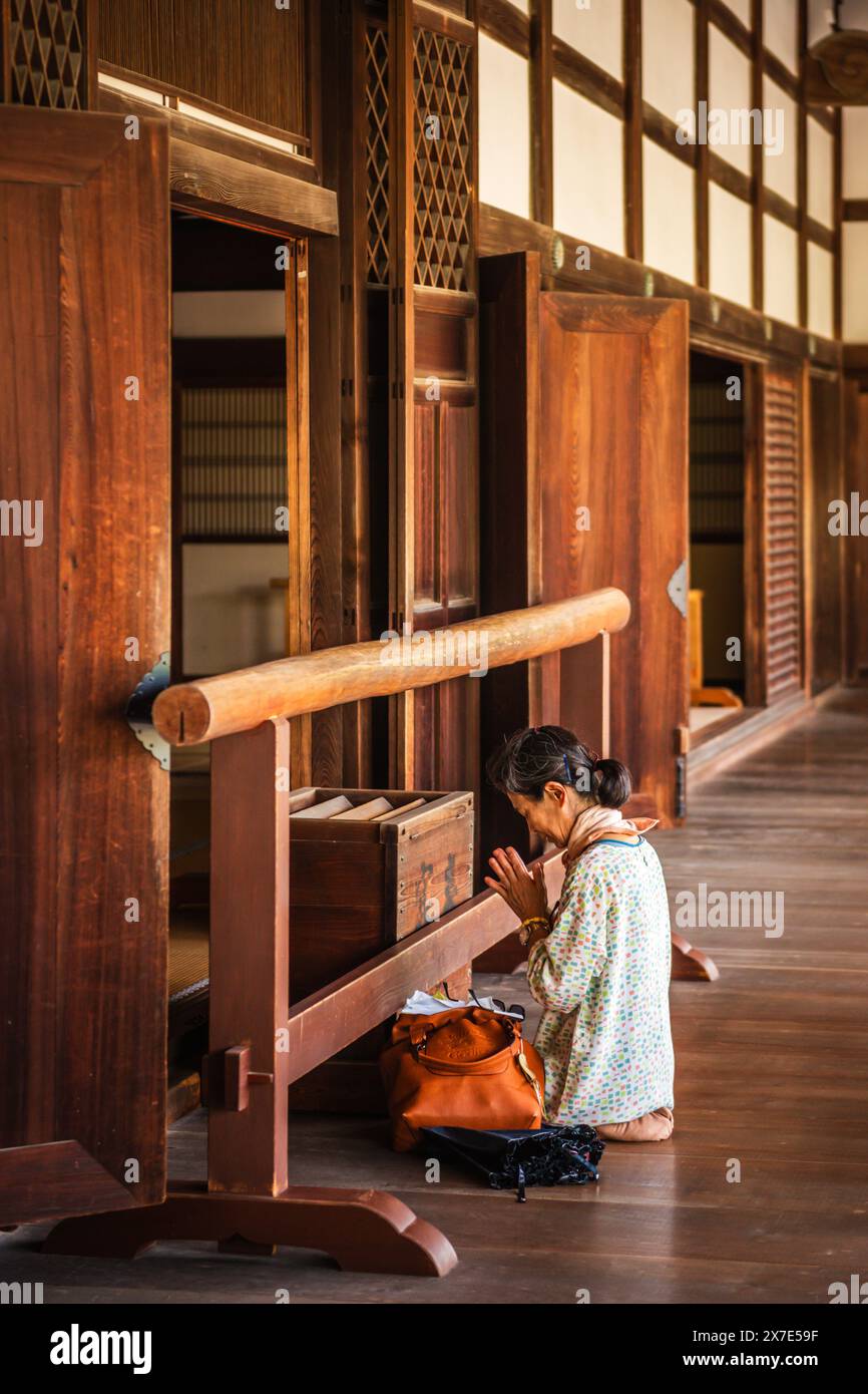 Kyoto, GIAPPONE - 27 luglio 2016: Immagine verticale della donna in preghiera all'interno del tempio. Foto Stock