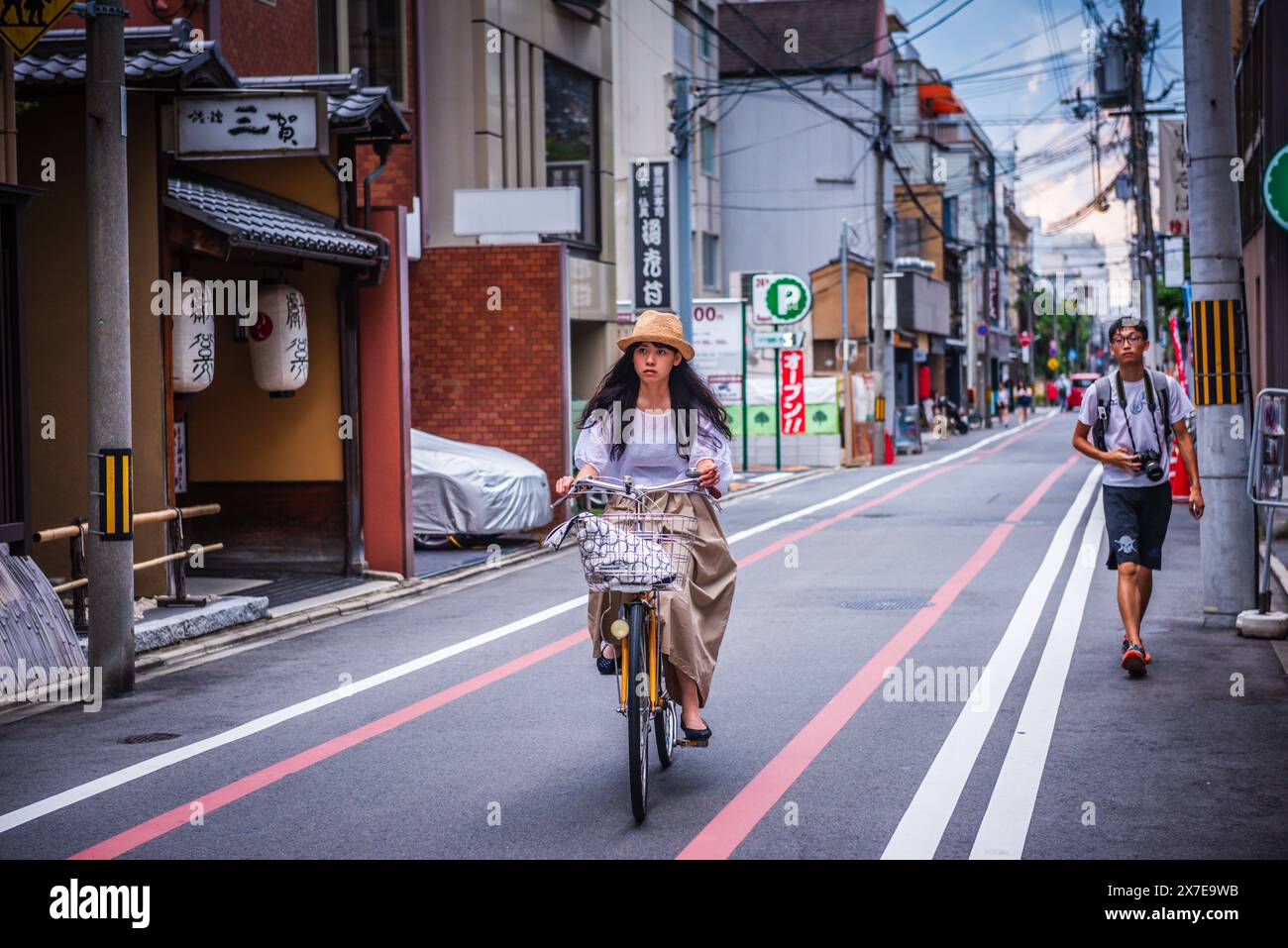 Kyoto, GIAPPONE - 30 luglio 2016: Elegante ragazza pedala in bicicletta lungo la stretta strada di Kyoto. Foto Stock