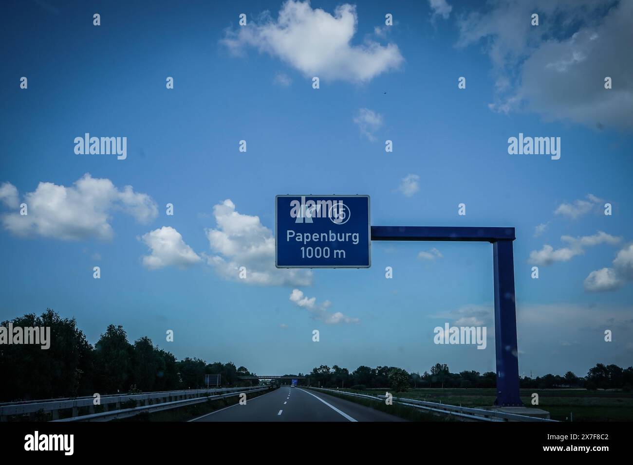 Autobahn, Straßenschild, Papenburg, 1000 m, Autobahnausfahrt, Ausfahrt 15, blauer Himmel, Wolken, Auto, Fahrbahn, Leitplanke, Bäume, Deutschland, Verkehr, Sommer, Kilometerangabe, Wegweiser, Autobahn A31, Emslandautobahn, Nord-Süd-Verbindung, Schnellstraße, Infrastruktur, Verkehrsnetz, 241 km Länge, verbindet Emden mit Bottrop, gebaut zwischen 1967 und 2004, wichtige Route für Urlauber, führt durch Niedersachsen und Nordrhein-Westfalen, landschaftlich reizvoll, wenig befahren, ermöglicht schnelle Verbindungen, geringe Verkehrsbelastung, Wichtige Verbindung für regionale Wirtschaft, erleichtert Foto Stock