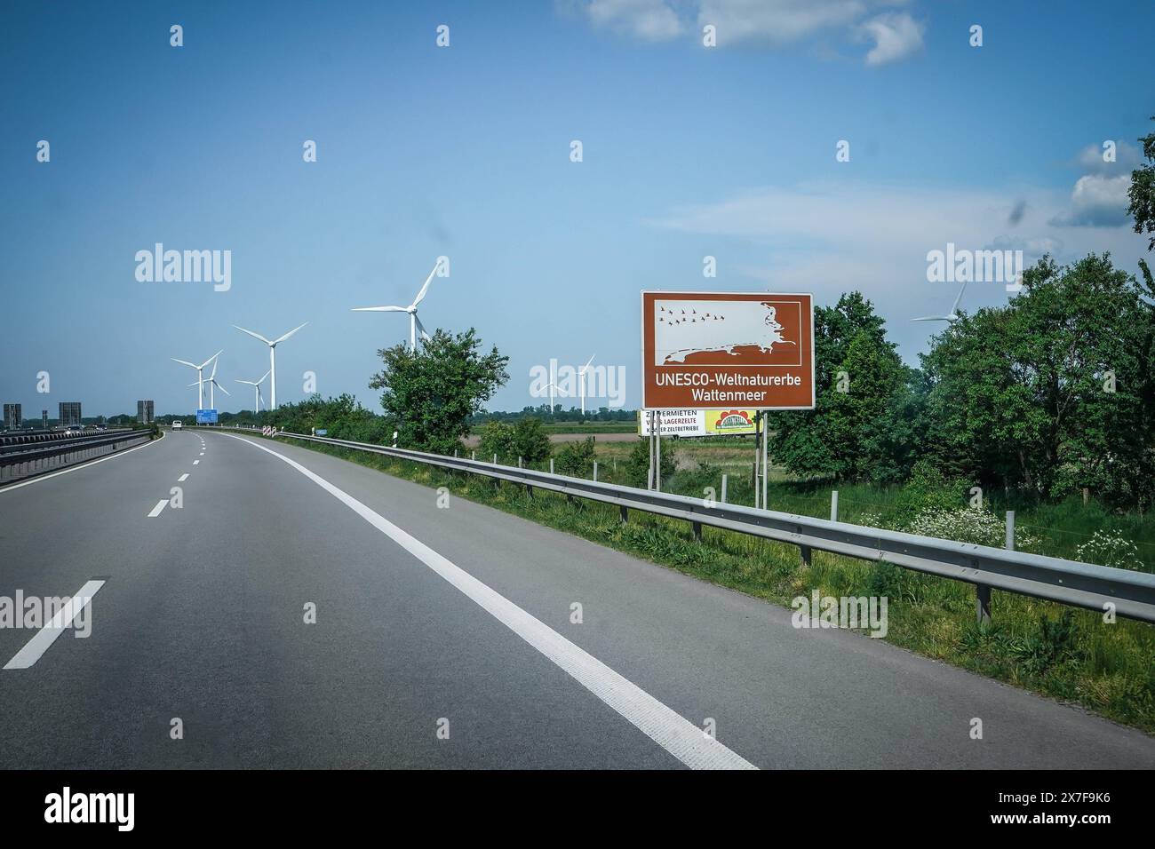 Autobahn, Straßenschild, UNESCO-Weltnaturerbe Wattenmeer, Braunes Schild, Windräder, blauer Himmel, Autobahn A31, Verkehrsschild, Auto, Fahrbahn, Leitplanke, Bäume, Deutschland, Verkehr, Sommer, Wegweiser, Emslandautobahn, Nord-Süd-Verbindung, Schnellstraße, Verkehrsnetz, 241 km da Emden, Bottrop, gebaut 1967-2004, wichtige Route Niedersachsen, Nordrhein-Westfalen, landschaftlich reizvoll, wenig befahren, schnelle Verbindungen, regionale Wirtschaft, Tourist ische Ziele, Umwelt, Naturschutz, erneuerbare energie **** Freeway, cartello, Patrimonio dell'Umanità dell'UNESCO, cartello marrone, turbine eoliche, b Foto Stock
