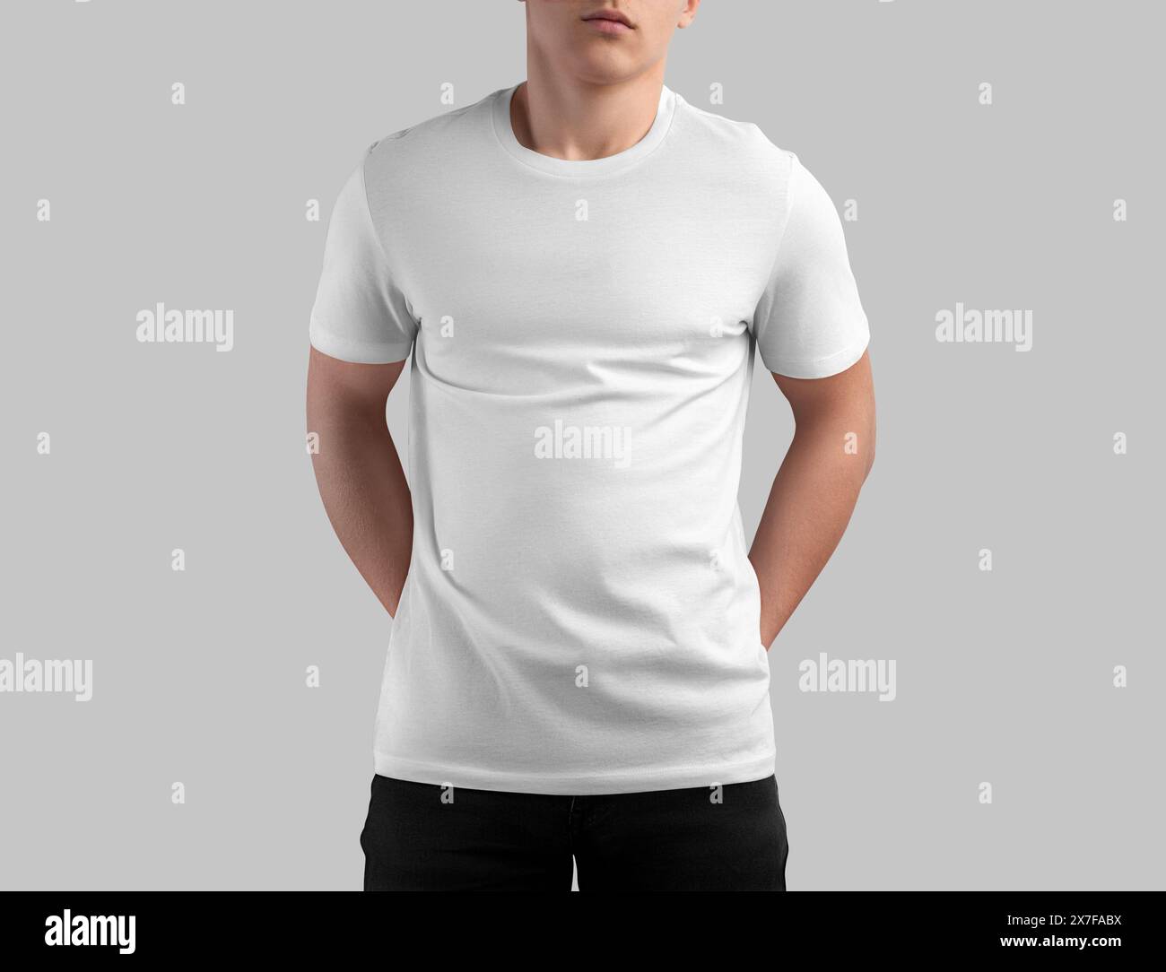 Modello t-shirt bianco su un ragazzo in jeans scuro con le mani dietro la schiena, vista frontale, isolata sullo sfondo. Mockup di camicia testurizzata, abiti maschili per des Foto Stock