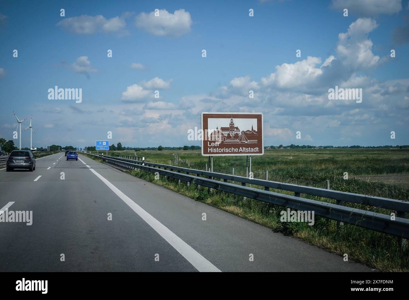 Autobahn, Straßenschild, Leer, Historische Altstadt, Braunes Schild, Windräder, blauer Himmel, Autobahn A31, Verkehrsschild, Auto, Fahrbahn, Leitplanke, Wiesen, Deutschland, Verkehr, Sommer, Wegweiser, Emslandautobahn, Nord-Süd-Verbindung, Schnellstraße, Verkehrsnetz, 241 km, Emden, Bottrop, gebaut 1967-2004, percorso wichtige, Niedersachsen, Nordrhein-Westfalen, landschaftlich reizvoll, wenig befahren, schnelle Verbindungen, regionale Wirtschaft, Tourist ische Ziele, Umwelt, Naturschutz, Parkplatz, Piktogramm *** Freeway, cartello stradale, Leer, centro storico, cartello marrone, turbine eoliche, cielo blu, A3 Foto Stock