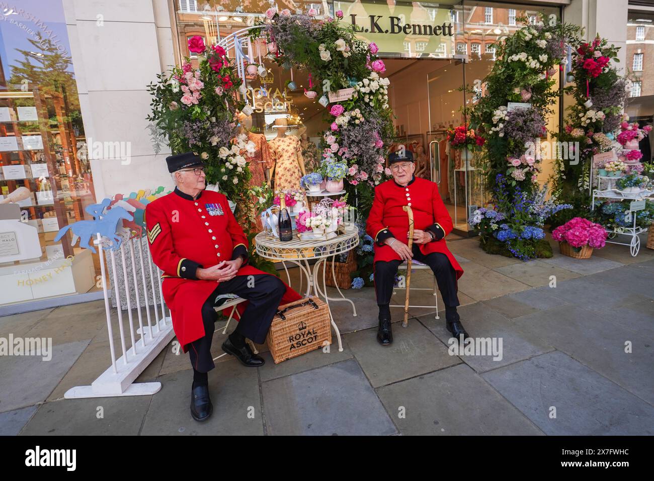 Londra, Regno Unito. 20 maggio 2024. Chelsea Pensioners seduti fuori dal L.. Negozio K Bennet su King's Road. Negozi che espongono esposizioni floreali a Chelsea in Bloom associati alla Royal Horticultural Society (RHS), la competizione annuale con i migliori rivenditori, ristoranti e hotel di Chelsea che si adornano di design creativi, competendo per gli ambiti premi. Il tema delle feste floreali di quest'anno, che riflette il patrimonio botanico e il cibo favoloso. Crediti: amer ghazzal/Alamy Live News Foto Stock