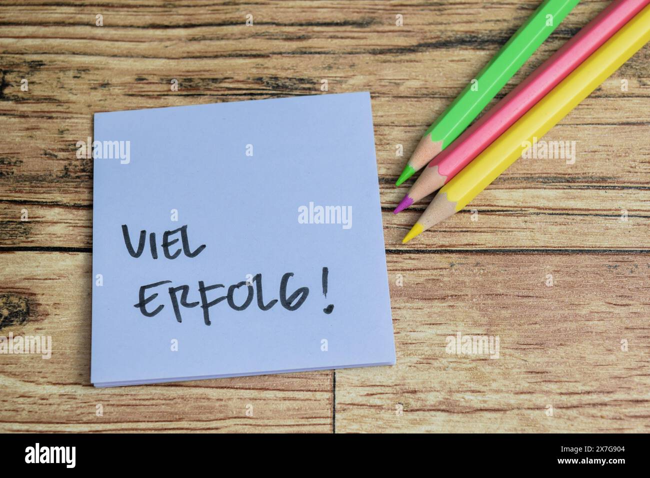 Concetto di apprendimento della lingua - tedesco. Viel Erfolg significa buona fortuna scritta su appunti. Lingua tedesca isolata su tavolo di legno. Foto Stock