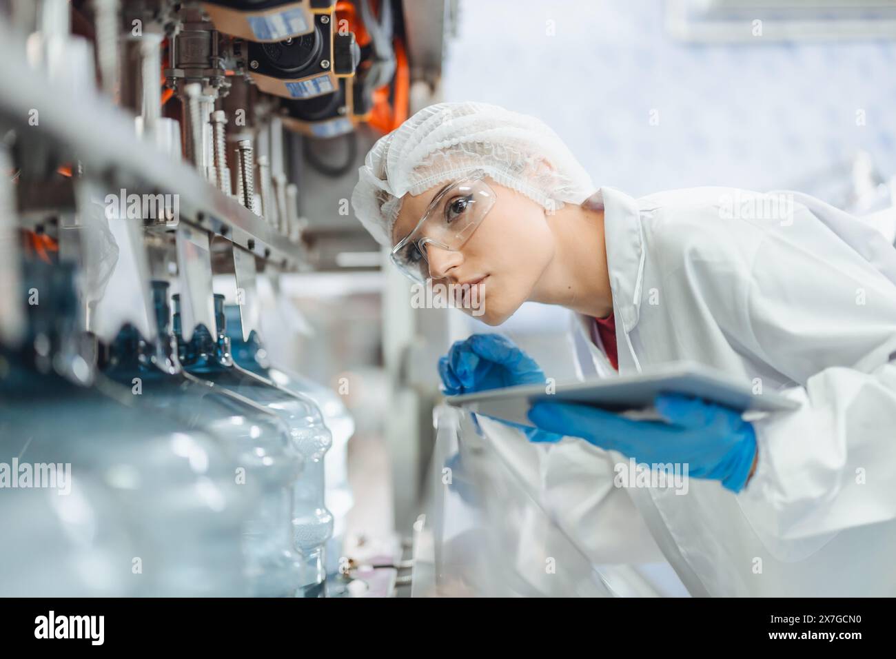 Le donne lavoratrici lavorano in fabbrica di acqua potabile controllare la qualità di controllo della macchina di rifornimento di acqua potabile funzionano Foto Stock