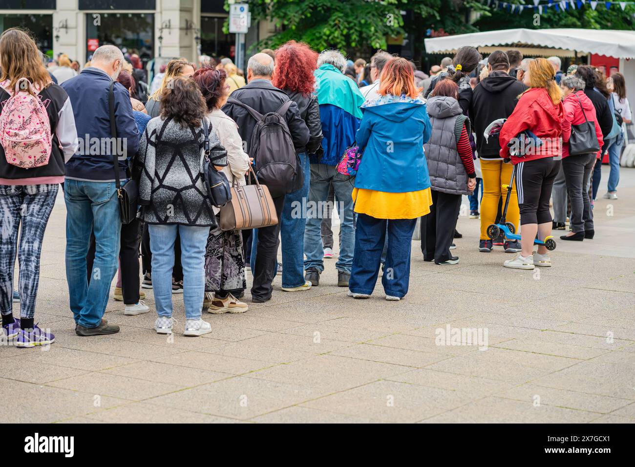 Folla di persone irriconoscibili che aspettano in fila per strada, fila di persone, vista dal retro Foto Stock