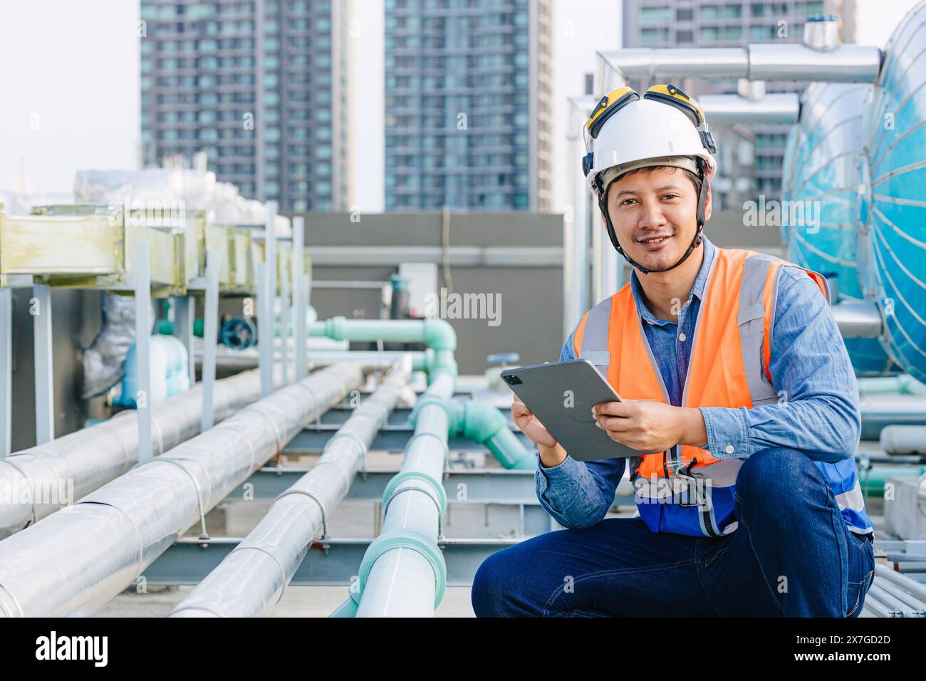 ritrattista ingegnere di tubi del gas in loco addetto alla manutenzione serbatoio dell'acqua calda sul tetto dell'edificio commerciale all'aperto sorridente. Foto Stock