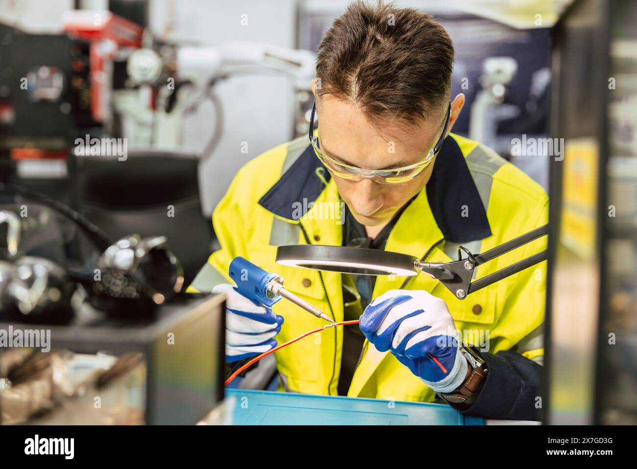 Tecnico elettricista maschio caucasico che utilizza un saldatore a caldo per il collegamento elettrico filo elettrico riparare il cavo della linea elettrica con stagno per saldatura e lea Foto Stock