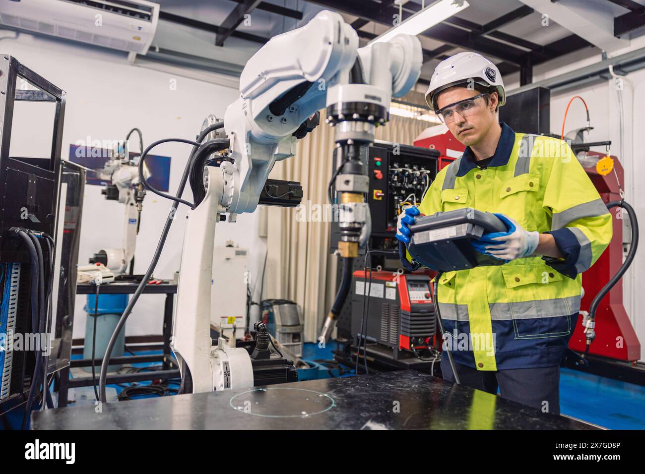 Ingegnere giovane studente universitario impara a controllare il braccio di saldatura robotizzato del settore in classe di laboratorio di ingegneri robotici nel politecnico Foto Stock