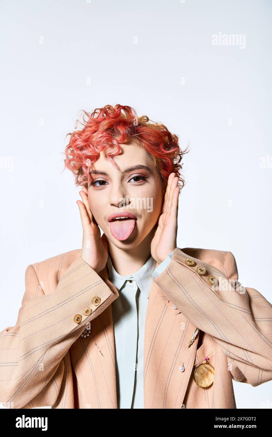 Una donna vibrante con i capelli rossi in un abbigliamento colorato si attacca con giocosità sulla lingua. Foto Stock