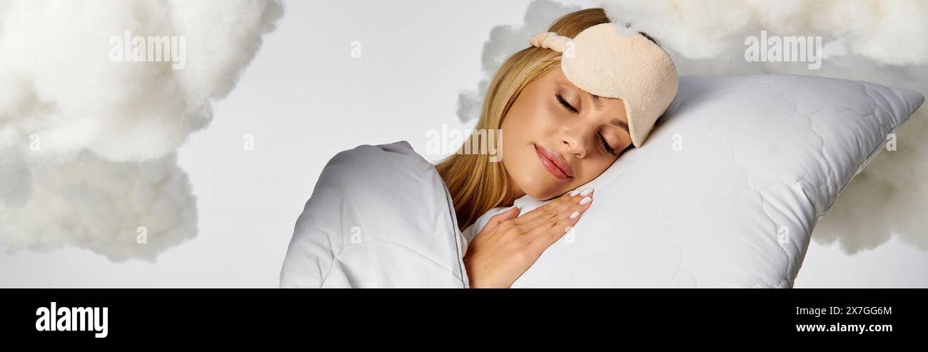 Una donna bionda in intimo pigiama che dorme tranquillamente su un cuscino tra soffici nuvole. Foto Stock